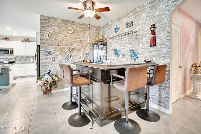 316 Nowell Loop, Deland, FL 32724 - indoor bar featuring appliances with stainless steel finishes, light tile patterned floors, ceiling fan, arched walkways, and backsplash