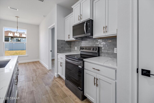 45 Fenhill Ln, Palm Coast, FL 32137 - kitchen with stainless steel electric range oven, backsplash, white cabinetry, light wood-type flooring, and a chandelier