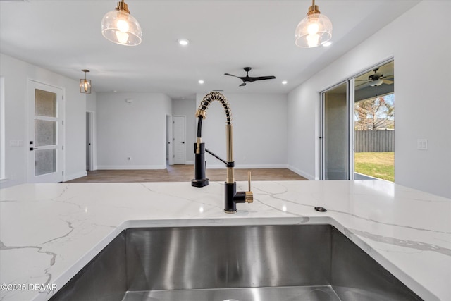 45 Fenhill Ln, Palm Coast, FL 32137 - kitchen view of light stone countertops, hanging light fixtures, a sink, wood finished floors, and recessed lighting