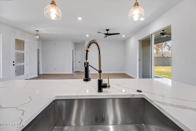 45 Fenhill Ln, Palm Coast, FL 32137 - kitchen view of light stone countertops, hanging light fixtures, a sink, wood finished floors, and recessed lighting