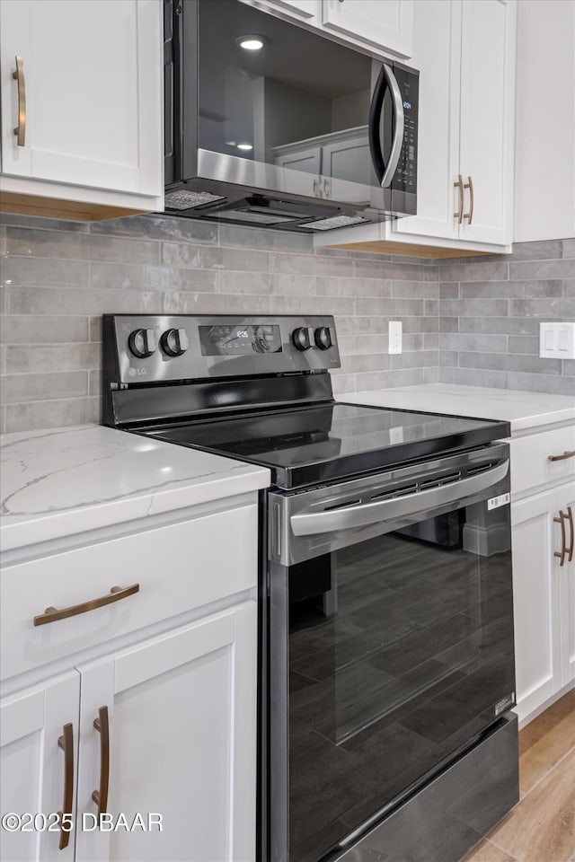 45 Fenhill Ln, Palm Coast, FL 32137 - kitchen featuring stainless steel appliances, white cabinets, tasteful backsplash, and light stone counters