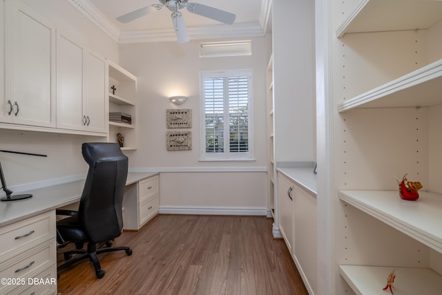 office area featuring built in desk, crown molding, a ceiling fan, and wood finished floors