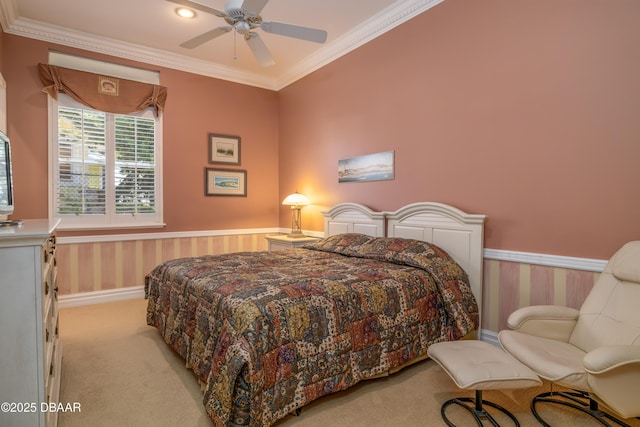 bedroom with ornamental molding, a wainscoted wall, and light colored carpet