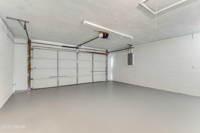 garage with concrete block wall, electric panel, and a garage door opener