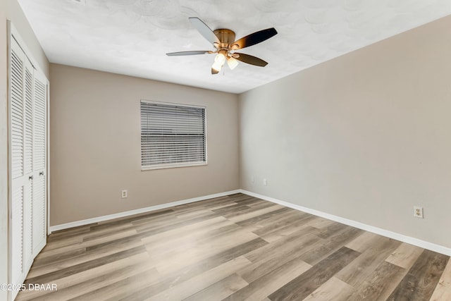 unfurnished bedroom featuring a closet, light wood-style flooring, baseboards, and ceiling fan