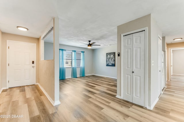 foyer entrance with baseboards, light wood finished floors, and ceiling fan