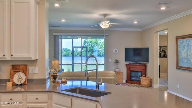 4119 Clifden Dr, Ormond Beach, FL 32174 - kitchen with a sink, a ceiling fan, open floor plan, a glass covered fireplace, and ornamental molding