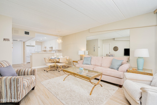 living room with an inviting chandelier and light hardwood / wood-style flooring