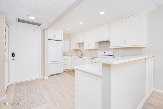 kitchen featuring sink, kitchen peninsula, light hardwood / wood-style floors, white appliances, and white cabinets