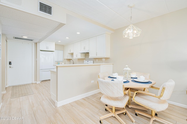 dining space featuring a chandelier, sink, and light hardwood / wood-style floors