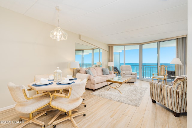 living room with expansive windows, a water view, a notable chandelier, and light wood-type flooring