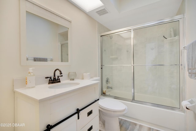 full bathroom with toilet, enclosed tub / shower combo, vanity, and hardwood / wood-style flooring