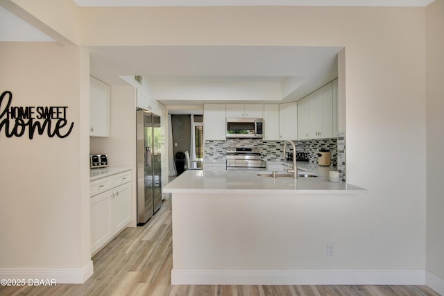 kitchen featuring kitchen peninsula, appliances with stainless steel finishes, white cabinetry, and sink