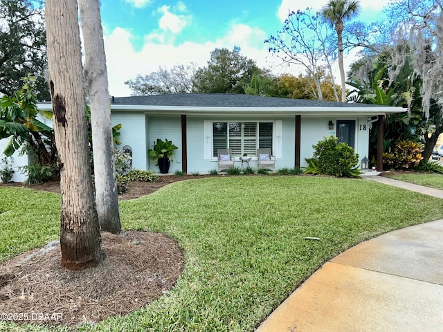 ranch-style home with a front yard and roof with shingles