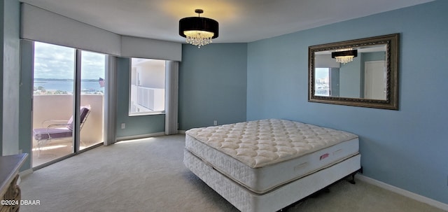 carpeted bedroom featuring multiple windows, a notable chandelier, and a water view