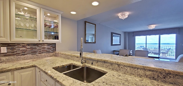 kitchen featuring white cabinetry, decorative backsplash, sink, and light stone counters