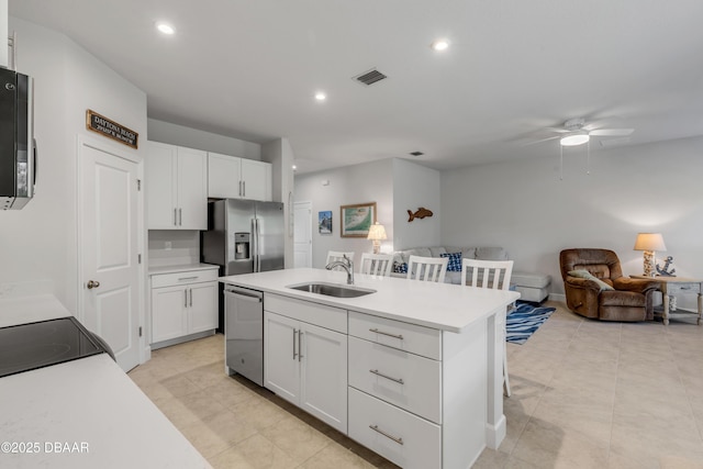 kitchen with a kitchen island with sink, appliances with stainless steel finishes, ceiling fan, white cabinets, and sink