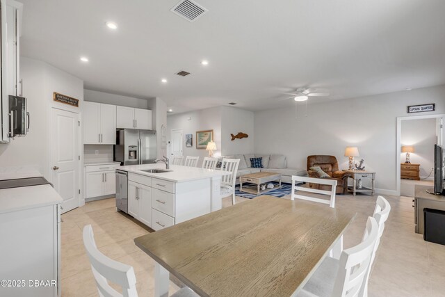 kitchen with appliances with stainless steel finishes, white cabinets, sink, and a center island with sink