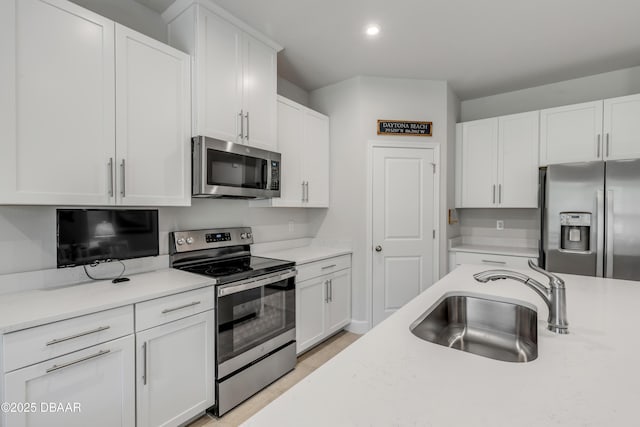 kitchen featuring appliances with stainless steel finishes, white cabinetry, and sink