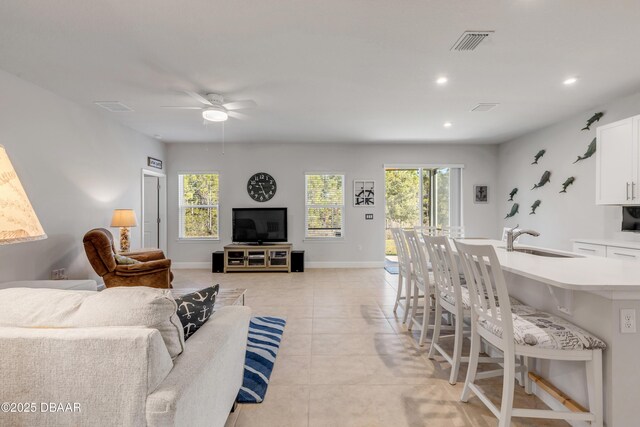 living room featuring sink, ceiling fan, and light tile patterned floors