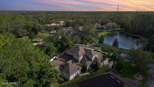 aerial view at dusk featuring a water view and a view of trees