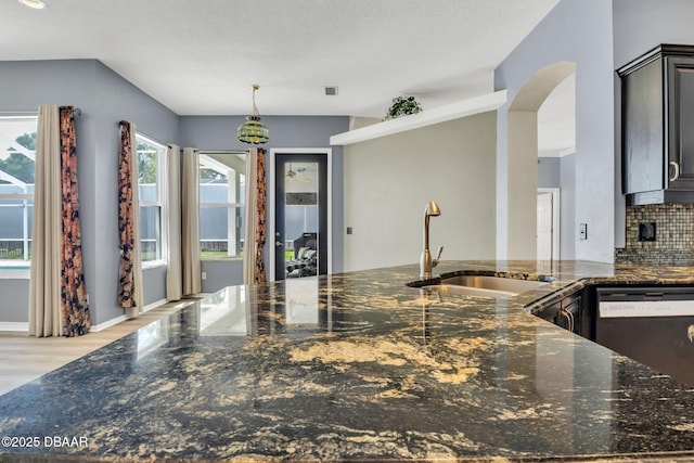 1001 Grassy Rdg, Port Orange, FL 32127 - kitchen with a sink, dishwasher, dark stone counters, light wood-style floors, and arched walkways