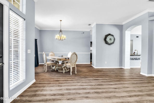 1001 Grassy Rdg, Port Orange, FL 32127 - dining space with ornamental molding, a chandelier, arched walkways, wood finished floors, and baseboards