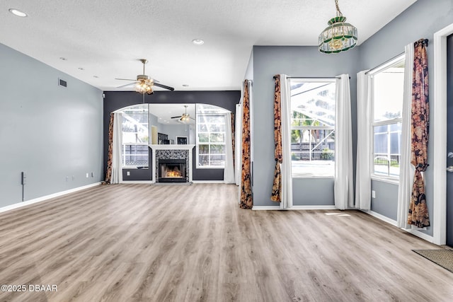 1001 Grassy Rdg, Port Orange, FL 32127 - unfurnished living room featuring ceiling fan, wood finished floors, plenty of natural light, baseboards, and a textured ceiling