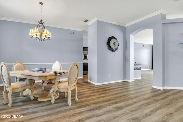 1001 Grassy Rdg, Port Orange, FL 32127 - dining area featuring arched walkways, crown molding, a chandelier, baseboards, and wood finished floors
