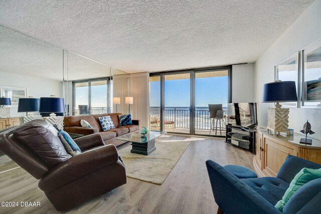 living room with a wall of windows, a textured ceiling, and light hardwood / wood-style flooring