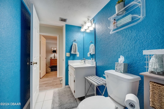 bathroom featuring toilet, vanity, wood-type flooring, and a textured ceiling