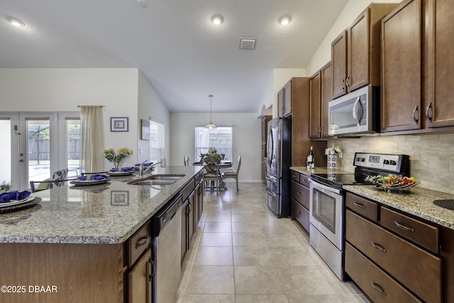 kitchen featuring tasteful backsplash, visible vents, a large island with sink, appliances with stainless steel finishes, and a sink