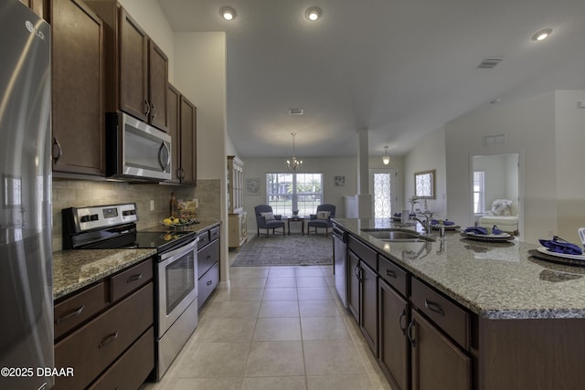 kitchen featuring visible vents, an island with sink, a sink, stainless steel appliances, and open floor plan