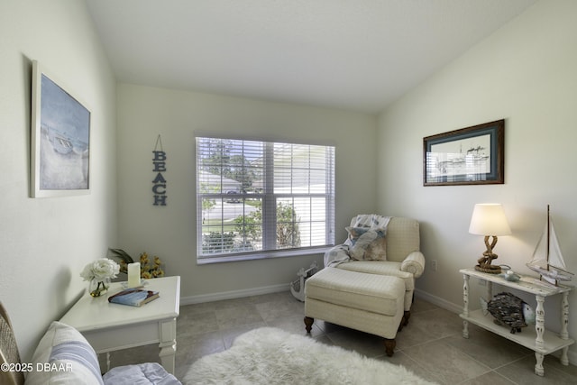 living area featuring tile patterned flooring, lofted ceiling, and baseboards