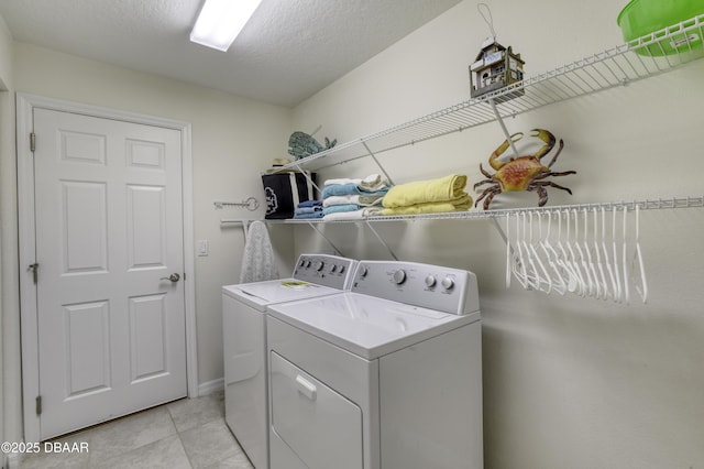 washroom with laundry area, light tile patterned floors, washing machine and dryer, and a textured ceiling