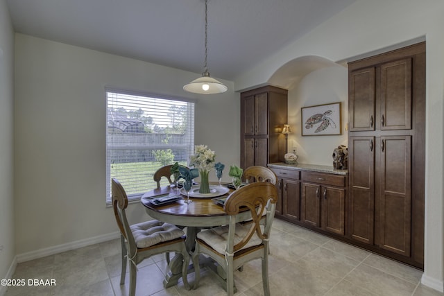 dining area with light tile patterned flooring, baseboards, and arched walkways