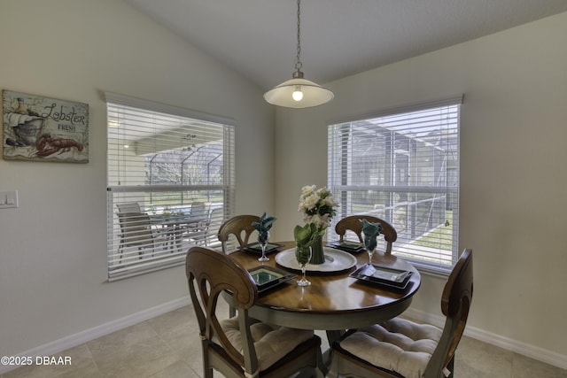 dining space with baseboards, lofted ceiling, and light tile patterned flooring