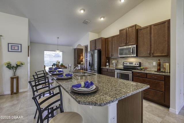 kitchen featuring visible vents, a sink, stainless steel appliances, a breakfast bar area, and lofted ceiling