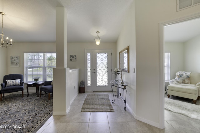 entryway with a wealth of natural light, visible vents, a notable chandelier, and light tile patterned floors