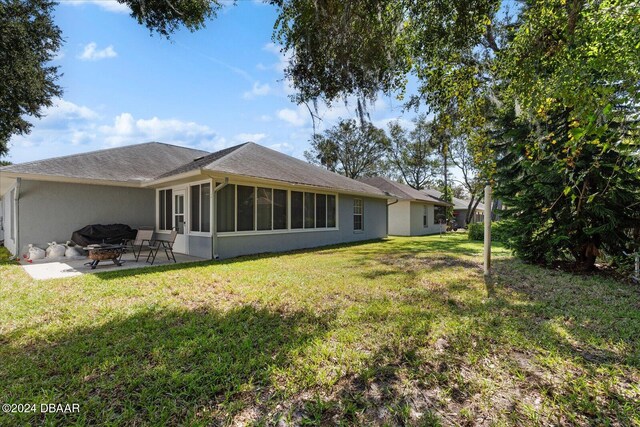 rear view of property with a lawn, a patio, and a sunroom