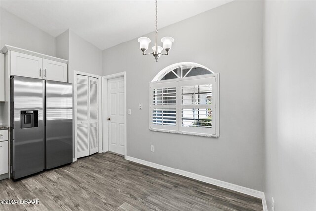 kitchen featuring white cabinetry, hardwood / wood-style floors, vaulted ceiling, and stainless steel fridge