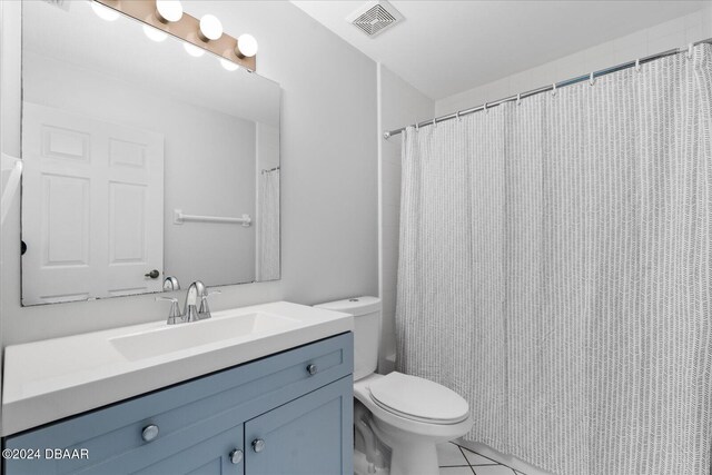 bathroom with toilet, walk in shower, vanity, and tile patterned floors