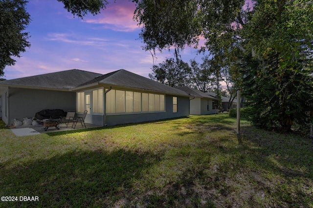 property exterior at dusk with a lawn and a patio area