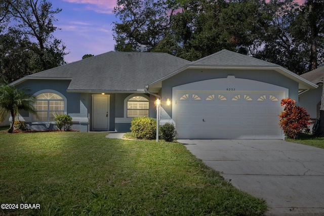 ranch-style house featuring a garage and a lawn