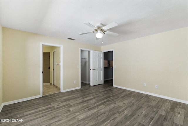 unfurnished bedroom with a spacious closet, dark hardwood / wood-style floors, ceiling fan, and a closet