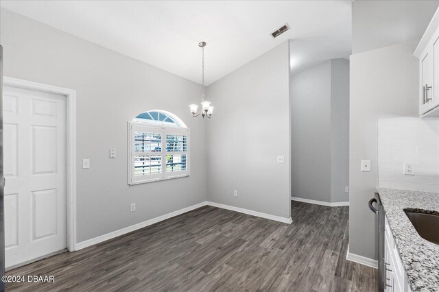 unfurnished dining area featuring dark wood-type flooring and a notable chandelier