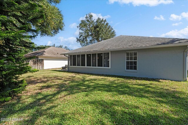 rear view of property with a sunroom and a yard