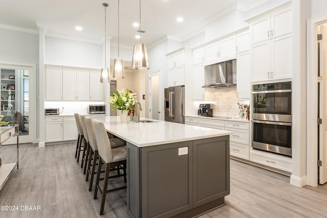 kitchen with appliances with stainless steel finishes, white cabinetry, and wall chimney exhaust hood