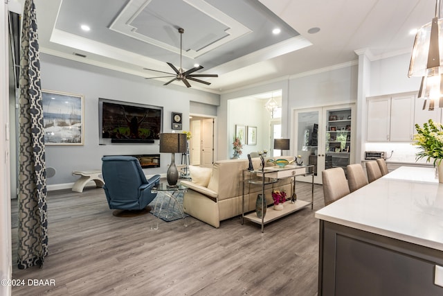 living room with hardwood / wood-style floors, french doors, a raised ceiling, and ceiling fan