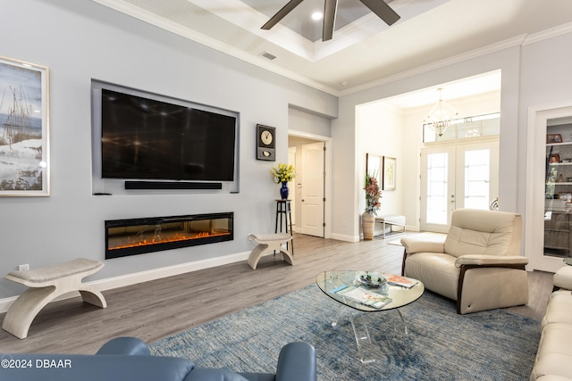 living room with wood-type flooring, ceiling fan with notable chandelier, and crown molding